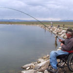Fisherman in a wheelchair fishing off the shore