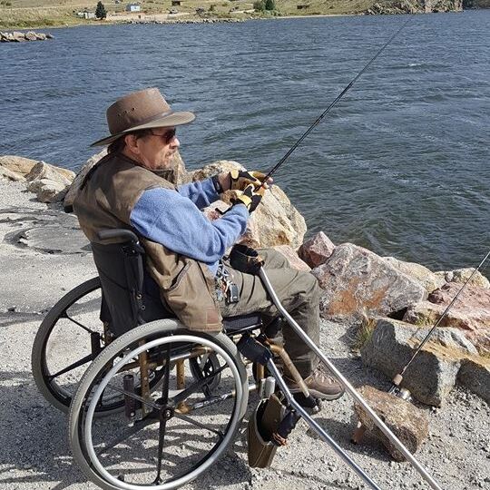 Man in wheelchair fishing off the shore